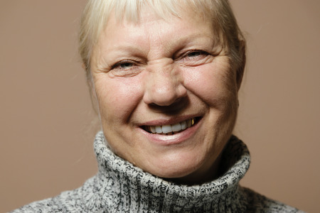 Middle aged woman portrait in sweater on beige background.の写真素材