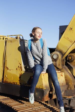 Young happy woman sitting on an yellow excavator.の写真素材