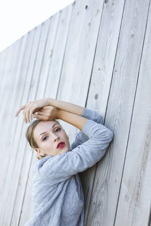 Young woman posing near a wooden wall.の写真素材