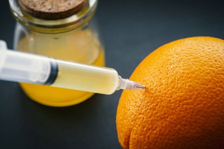 Orange with syringe injection colored liquid.の写真素材