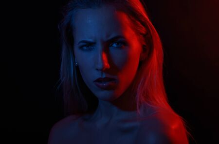 Portrait of a woman with colored light and dark background.の写真素材