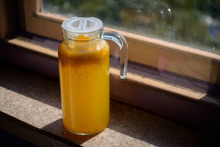 Glass carafe with compote from sea-buckthorn in the kitchen. Home made. Shallow depth of field.の写真素材