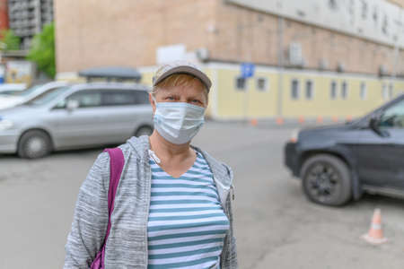 Aged woman on street wearing face mask during outbreak.の写真素材