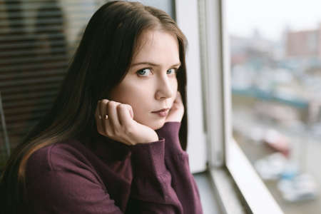 Sad woman looking through the window.の写真素材