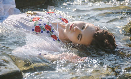 Young woman in white dress enjoys sea.