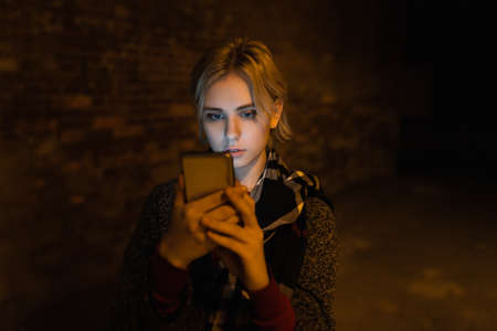 Young woman using smartphone on the street by night.の写真素材