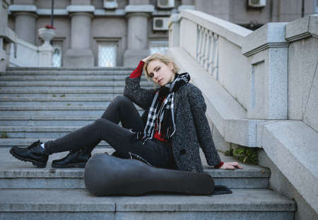 Beautiful girl in coat. With old case for violin in a hand.の写真素材