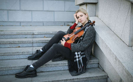 Beautiful girl in coat holding a old violin.の写真素材