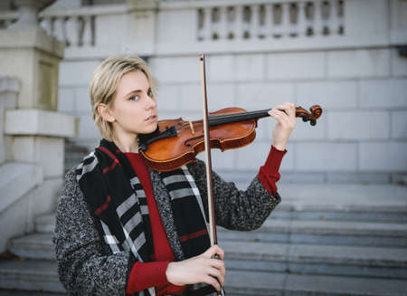 Beautiful girl in coat holding a old violin.の写真素材