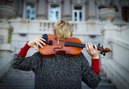 Beautiful girl in coat holding a old violin.の写真素材