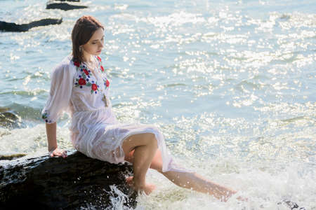 Young woman in white dress enjoys sea.の写真素材