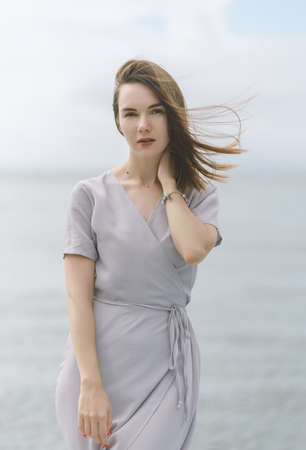 Woman in dress enjoys a walking near the sea shore.