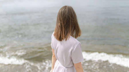 Woman in dress enjoys a walking near the sea shore.の写真素材