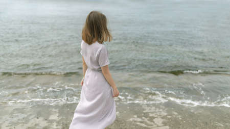 Woman in dress enjoys a walking near the sea shore.の写真素材