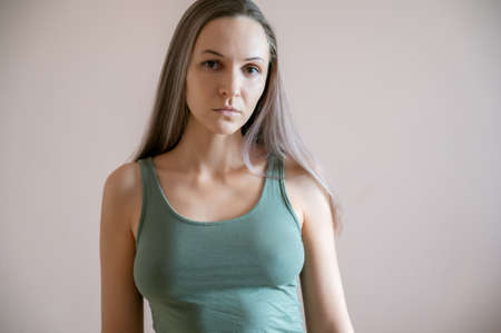 Graceful adult woman posing against beige wall.の写真素材