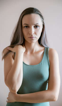 Graceful adult woman posing against beige wall.の写真素材