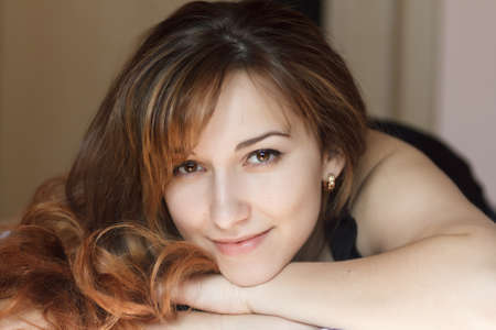 Closeup portrait of a beautiful young lady lying on the bed.の写真素材