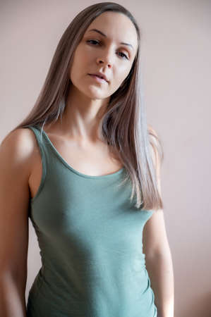 Graceful adult woman posing against beige wall.の写真素材