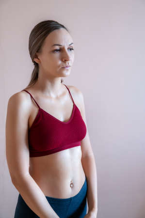 Graceful adult woman posing against beige wall.の写真素材