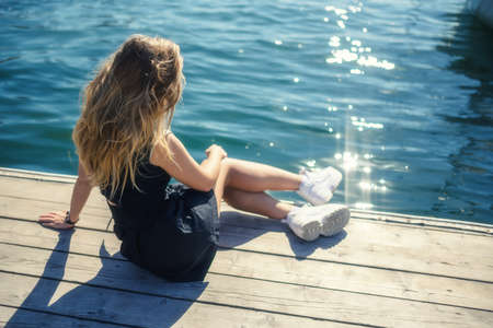 Woman in dress enjoys sea on the pier.の写真素材