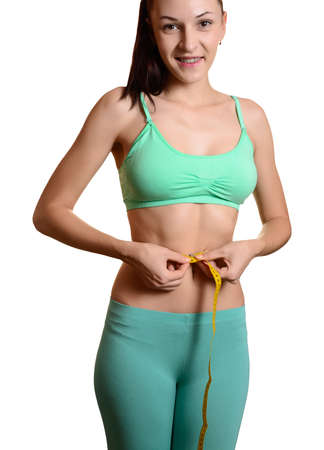 Fit and healthy young woman measuring her waist with a tape measure Isolated on white.の写真素材