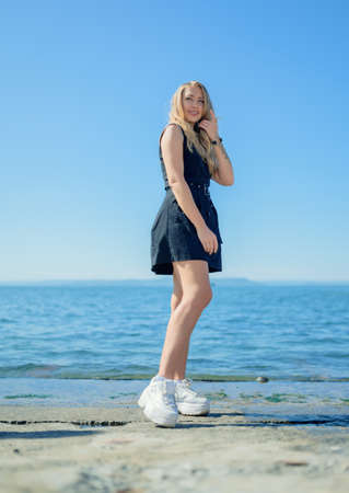 Woman in dress enjoys a walking near the sea shore.の写真素材