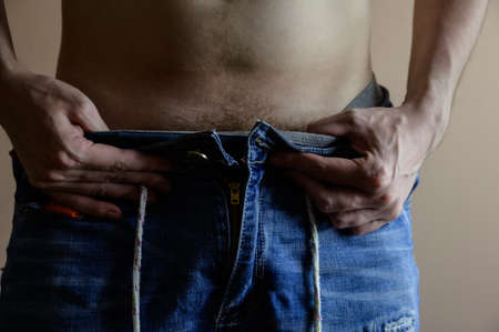 Man takes off his jeans. Selective focus.の写真素材