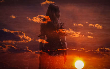Double exposure of young woman and sunset sky.の写真素材