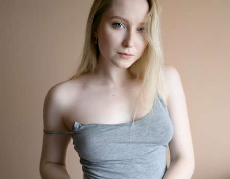 Graceful young woman posing against beige wall.の写真素材