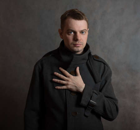 Young man in coat on dark background.の写真素材