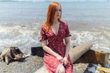 Young redhead woman in white dress enjoys sea.の写真素材