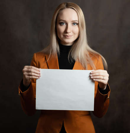Business woman portrait with papers in hand on dark background.