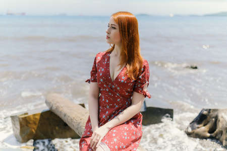 Young redhead woman in white dress enjoys sea.の写真素材