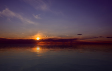 Dramatic sunset sky with clouds reflected in water surface.の写真素材