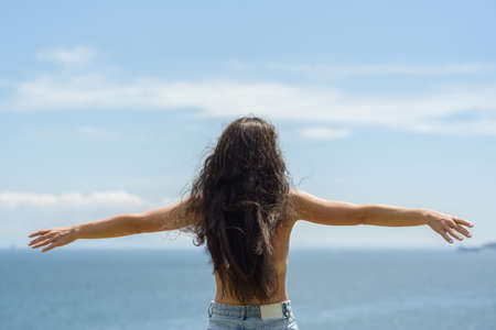 Beautiful adult woman enjoy the sea on a sunny day. view from back.の写真素材