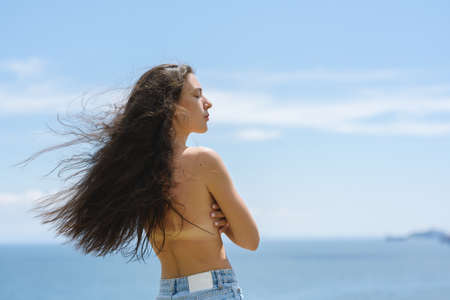 Beautiful adult woman enjoy the sea on a sunny day. view from back.の写真素材