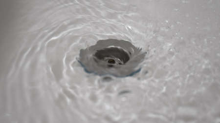 Water flowing down the hole in a kitchen sink.の写真素材