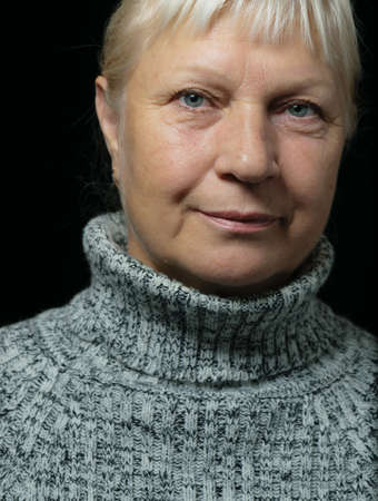 Middle aged woman portrait in sweater on dark background.の写真素材