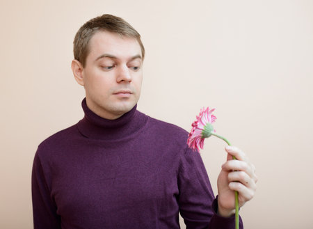 Young man holding gerbera flower in hand.の写真素材