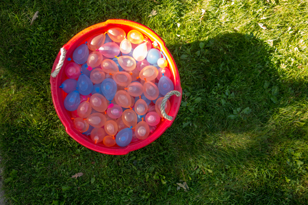 A bucket full of water balloons sitting in the grass ready for summer funの写真素材