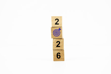 Wooden blocks stacked vertically spell out the year 2026, with a target symbol replacing one of the...