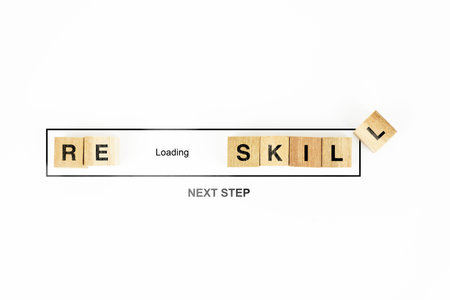 A conceptual image showing the word RESKILL spelled out with wooden tiles, accompanied by a loading bar and the phrase NEXT STEP.の写真素材