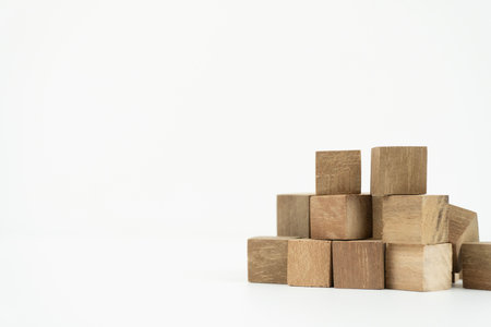 A pyramid-like structure of brown wooden blocks is arranged on a clean white background, creating a...