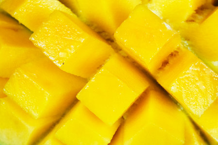 Close up bright yellow mango flesh shows juicy diced cubes ready for a sweet tropical dessert.