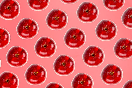 Vibrant red apples form a seamless repeating pattern against a monochromatic pink background.の写真素材