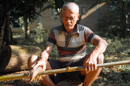 Elderly man crafting bamboo in a natural outdoor settingの写真素材