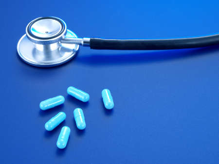 Stethoscope and blue pills on a blue background.の写真素材