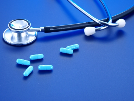 Stethoscope and blue pills on a blue background.の写真素材