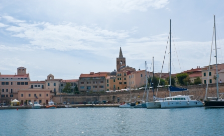 the yachts in the old haven of Alghero with the historic town centre on the background  Sardinia,...