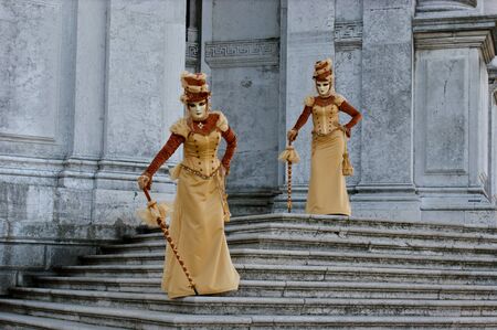 Two women in gorgeous dresses and masks in Veniceの写真素材